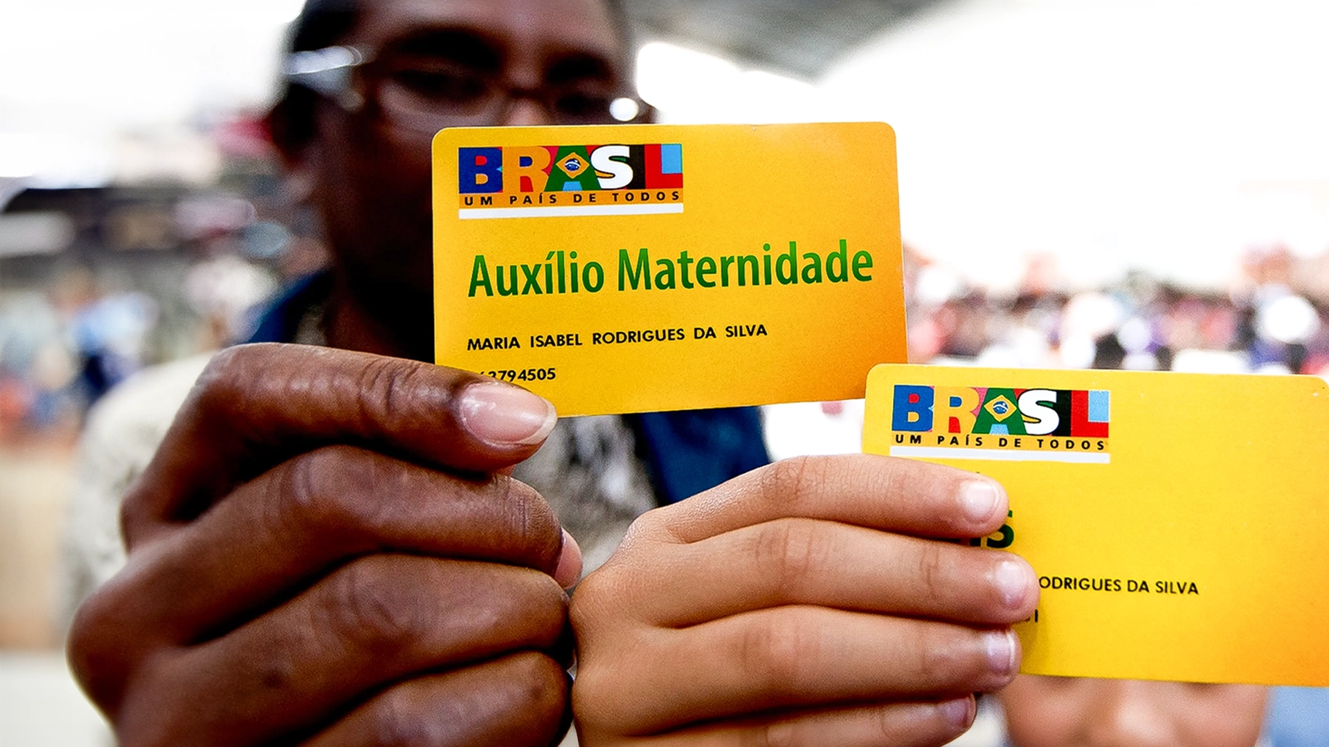 Mãe feliz segurando o cartão do benefício de Auxilio Maternidade